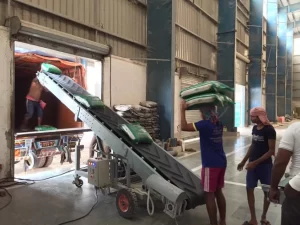 Labours are loading products into truck with the help of truck loading conveyor